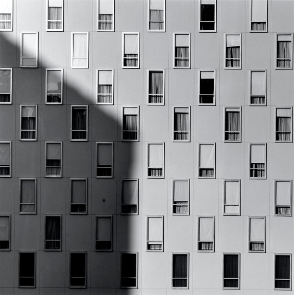 Series of rectangular apartment windows with a shadow across the left side of image.