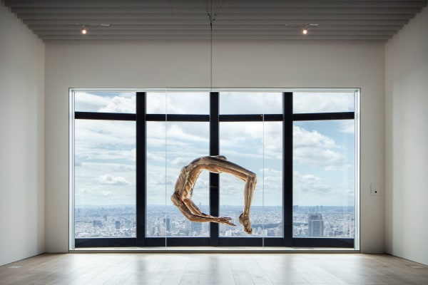 Installation view of "Arch of Hysteria" by Louise Bourgeois, at the Mori Art Museum. The Tokyo cityscape is visible through the window that frames the artwork.