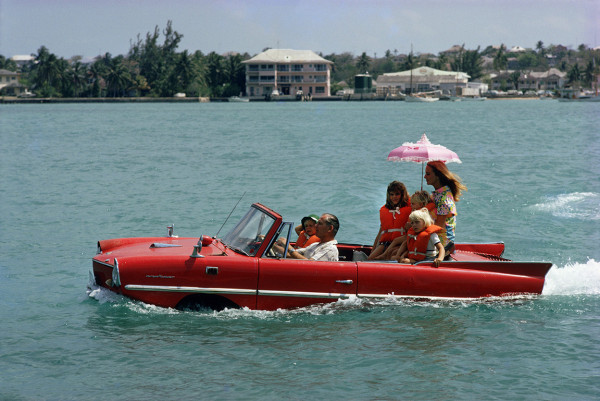 Slim Aarons, Sea Drive: Film producer Kevin McClory takes his wife Bobo Segrist and their family for a drive in an &quot;Amphicar&quot; across the harbor at Nassau, 1967