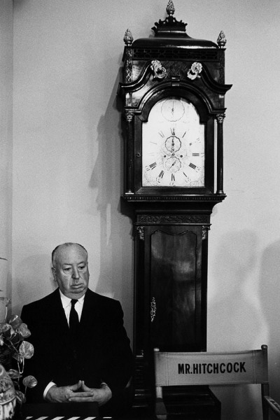 Bob Willoughby, Alfred Hitchcock next to the Grandfather clock on on the Universal Studios set of Marnie, 1964