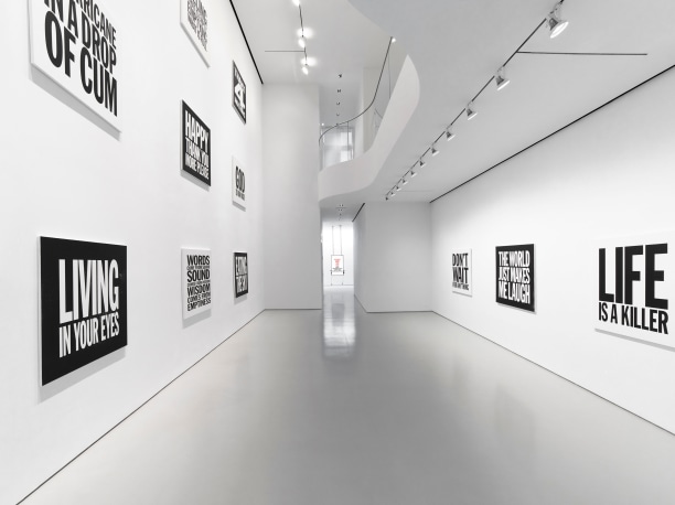 View across the main gallery with nine black and white square screen prints to the left and three on the right, each with excerpts from iconic John Giorno Poems. 