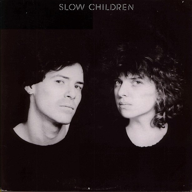 Album cover Slow Children, musicians  wearing black t-shirts photographed against black background.