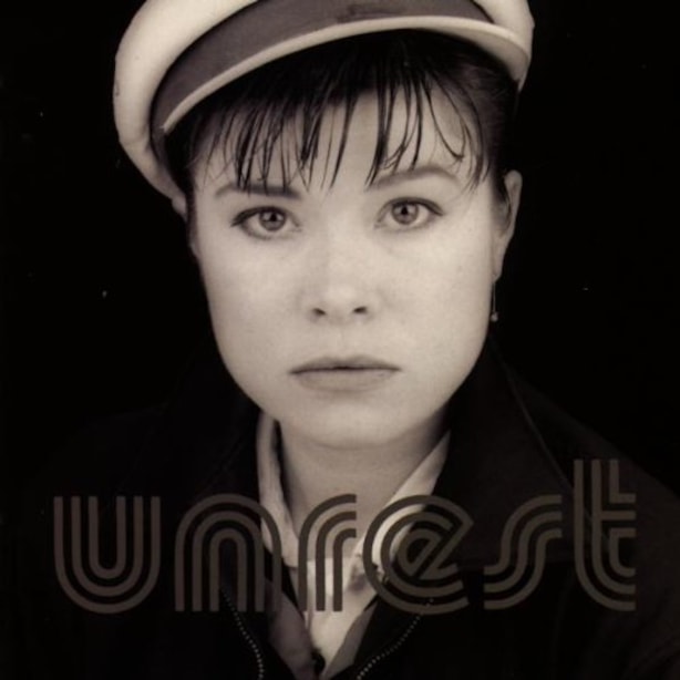 Album Cover, Unrest portrait of Cath Carroll in a white hat and bangs, staring at the camera.