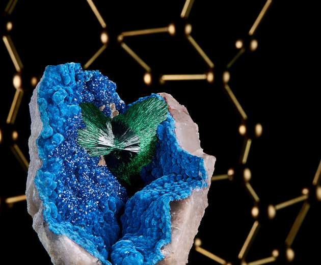 A fine mineral photograph of Malachite with a brass molecular model of malachite in the background.