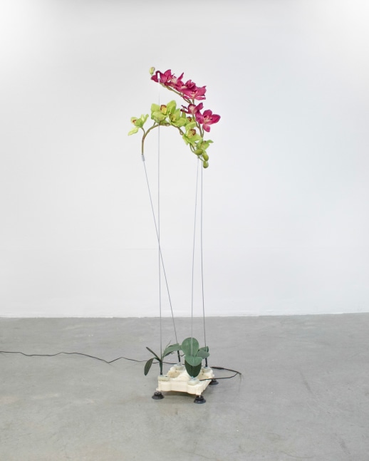 A sculpture of artificial flowers attached by wires to an electric massage machine