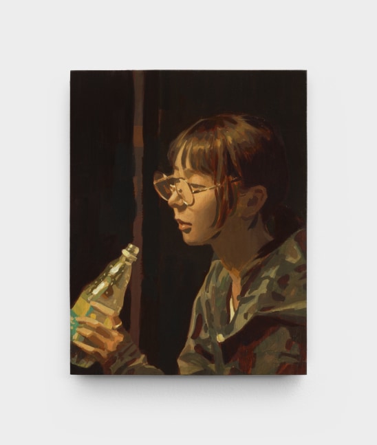 A portrait of a young woman in glasses drinking from a clear bottle.