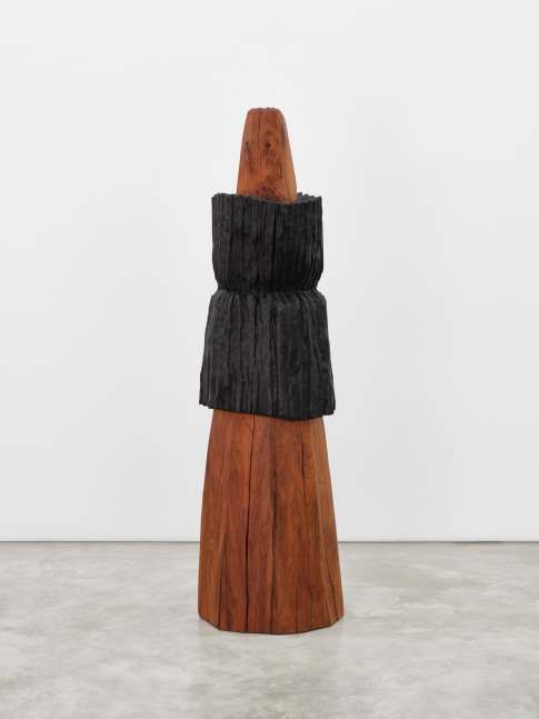 An elongated wooden cone shaped sculpture with a long black wooden carving fitted around its center.