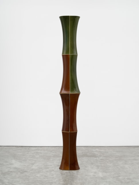 A freestanding ceramic sculpture with green and brown composite sloping parts.
