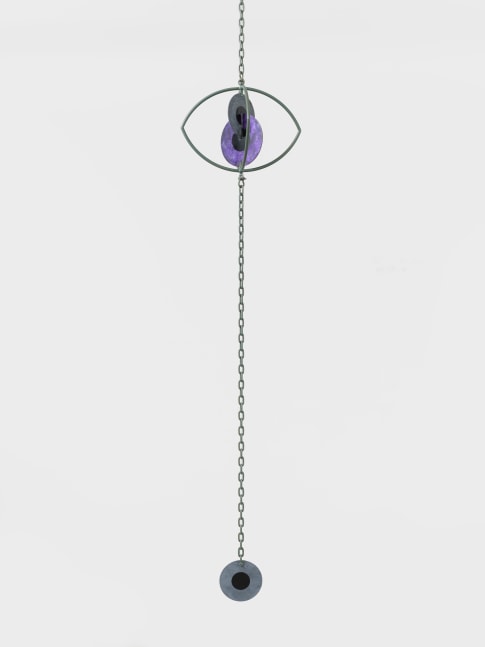 A hanging sculpture with two interlocking metal iris' inside a metal eye with a third iris hanging from a chain.