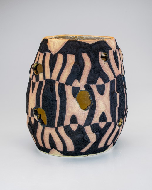 A small stoneware vase with openings and geometric patterns in earthy red and black paint.