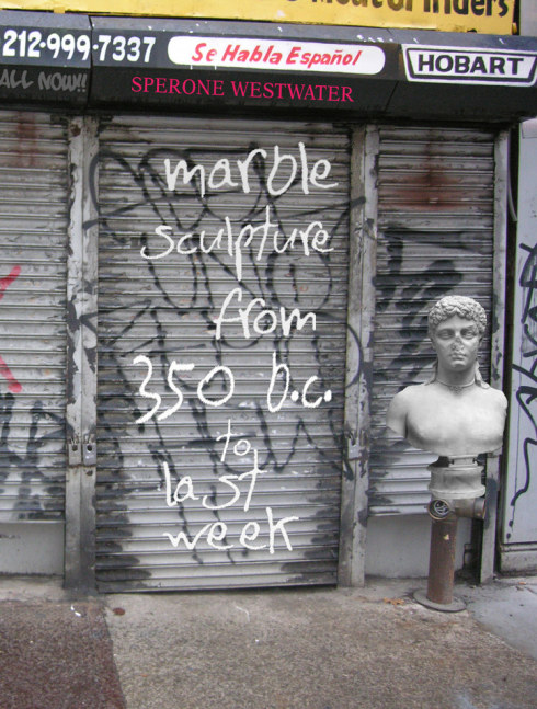 book cover with photograph of a storefront with rolldown gates covered with graffiti and a sculptural bust of a man on top of a water pipe
