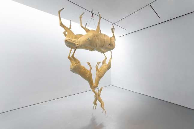 Large sculpture made of tan-colored taxidermy molds of deer-like animals, suspended from the ceiling in a cluster with limbs pointing outward