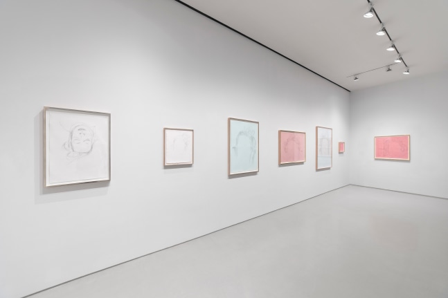 7 drawings on pink, blue, or white paper hanging on white wall