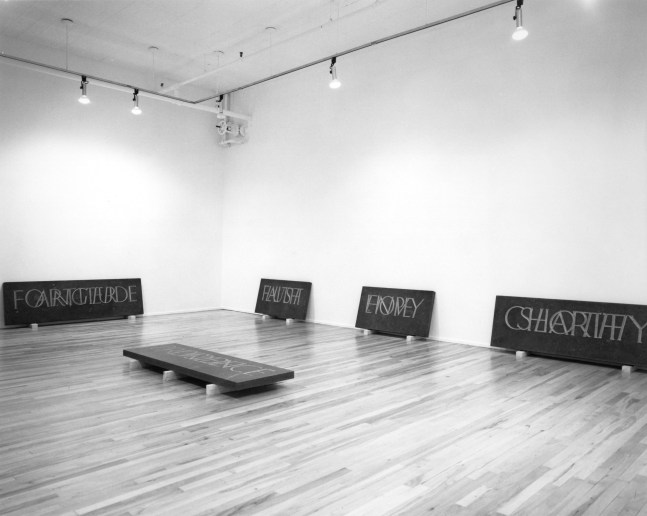 black and white installation view of five inscribed stone slabs place around a room