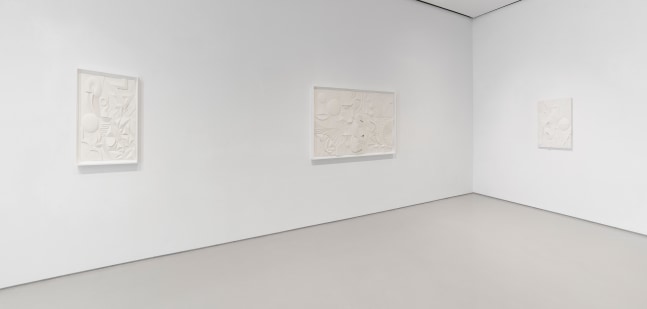 Installation view of two adjacent walls featuring three white artworks on white walls