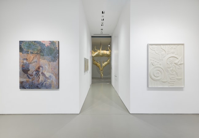 one artwork on each wall on either side of a hallway leading into a room with a sculpture of animals hanging from the ceiling