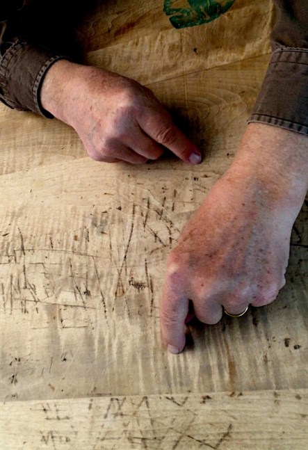 video still of two fists with index fingers extended resting on a scuffed and marked wooden table