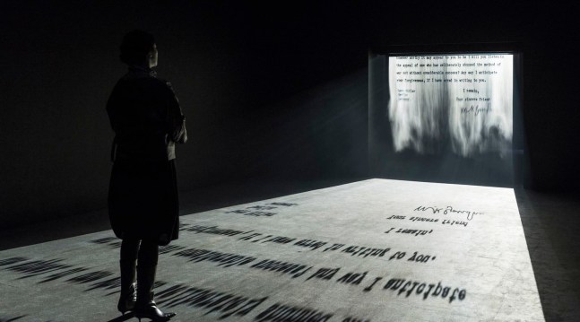a figure stands in a room looking at a fog screen projection