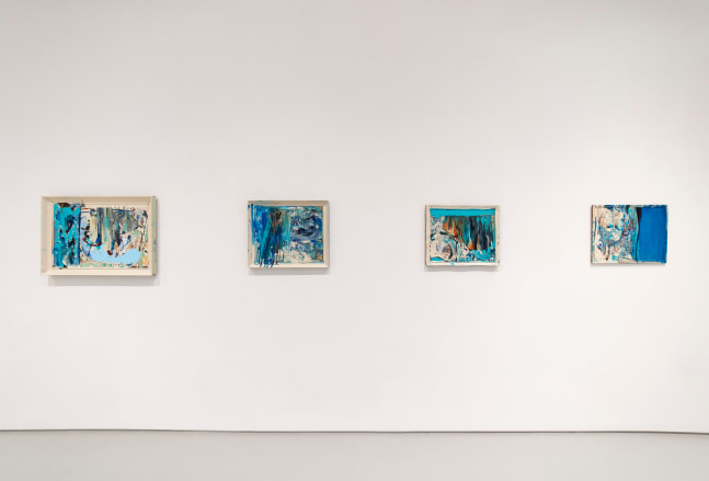 Four abstracted predominantly blue paintings placed horizontally on a white wall.