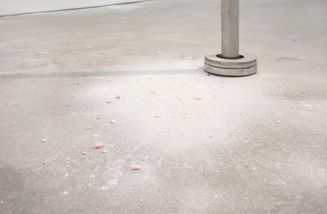 Installation shot of pink alabaster stone dust on ground beneath stainless steel pedestal.