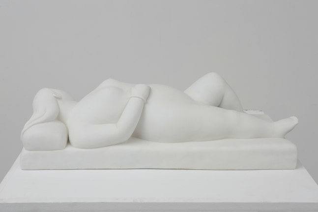 White marble sculpture of a reclining woman on pillow.