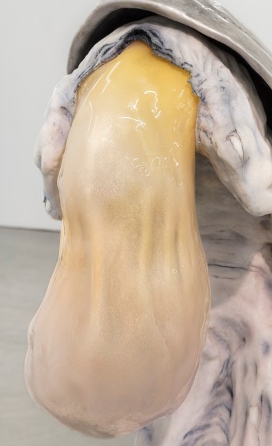 Detail of yellow glass blown oblong object emerging from humanoid figure.