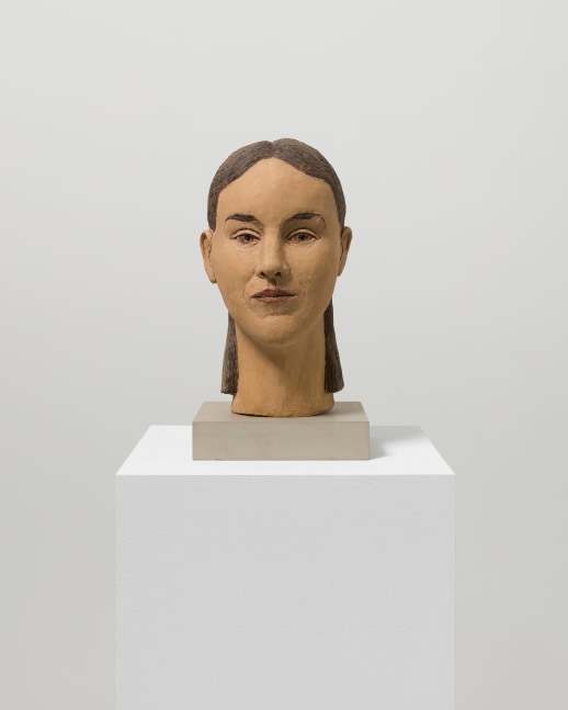 Painted fiberglass sculpture of a woman's head with brown hair and eyes