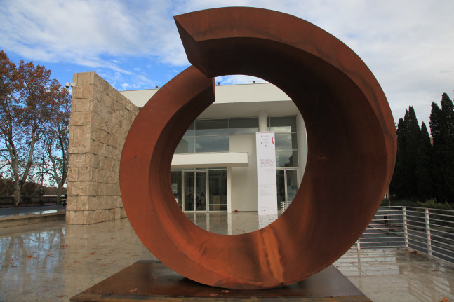 Circular abstract sculpture installed outside of a museum
