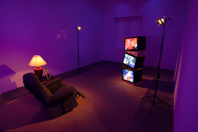 Ja'Tovia Gary, Precious Memories, 2020, SD video and SD video from 16mm film on 3 CRT monitors, acrylic, dried cotton, moss, dried helichyrsum, upholstered recliner chair, carpet, wood and glass table, framed photograph, table lamp, 2 stage lamps, monitor:  90 x 24 1/4 x 18 1/2 in. (2286 x 61.6 x 47 cm); installation: dimensions variable