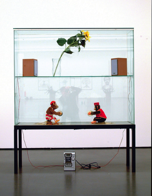 Sam Durant "Concert for Two Ideologies, Green, Fluxus Doubled Trickster" 2003 Vitrine, plastic sunflower, glass vase, CD player, cymbals, toy monkeys, car battery, transformer, photocopy collage in steel frame 70 3/4 x 59 x 19 3/4 in.