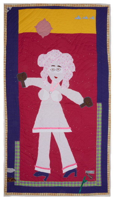 A narrow quilt depicting Dolly Parton in heels and a suit