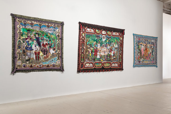 Installation view of artist Myrlande Constant's Vodou flags hung up on a white wall.