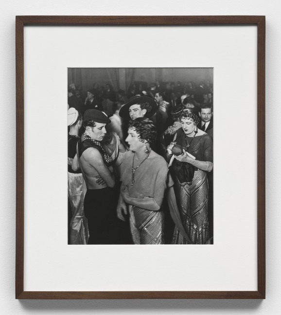 A black and white photographic print by Brassai depicting a crowded room at the Magic-City drag ball