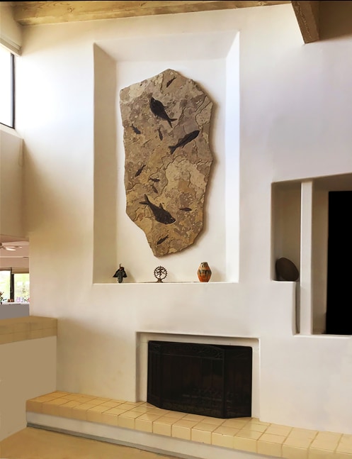 A tall vertical irregularly shaped fossil fish mural rests in an alcove of a modern Arizona home