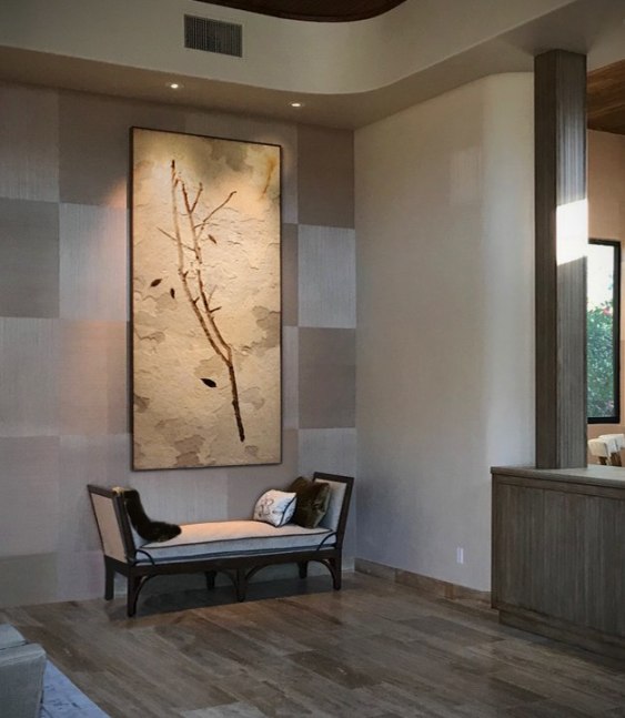A giant fossil mural featuring a 50 million year old branch with leaves hangs in a modern home