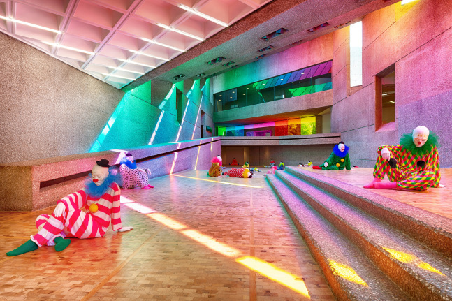Installation view of colorful clown sculptures and rainbow colored windows by Ugo Rondinone