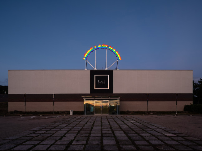 Installation view of outdoor neon sign saying long last happy by Ugo Rondinone