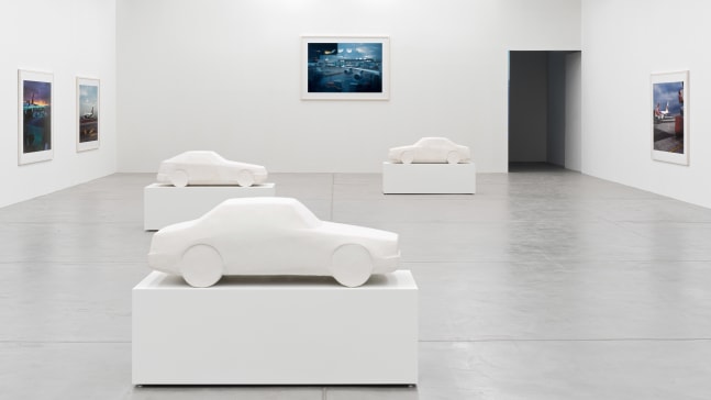 installation view of photographs of airports and car sculptures by Peter Fischli and David Weiss