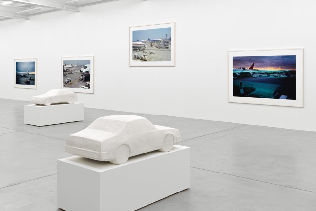 installation view of photographs of airports and car sculptures by Peter Fischli and David Weiss