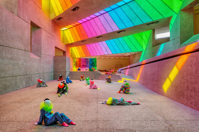 Installation view of colorful clown sculptures and rainbow colored windows by Ugo Rondinone