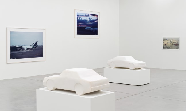 installation view of photographs of airports and car sculptures by Peter Fischli and David Weiss
