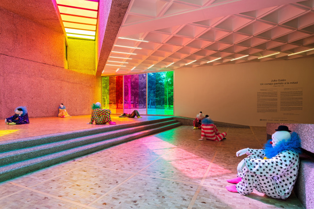 Installation view of colorful clown sculptures and rainbow colored windows by Ugo Rondinone