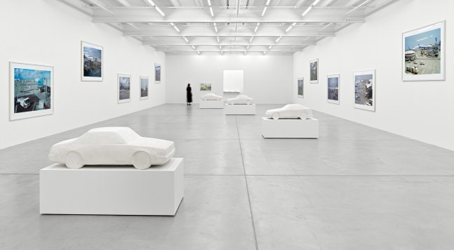 installation view of photographs of airports and car sculptures by Peter Fischli and David Weiss