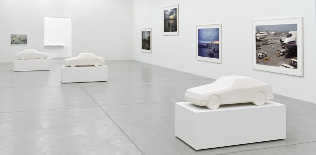 installation view of photographs of airports and car sculptures by Peter Fischli and David Weiss