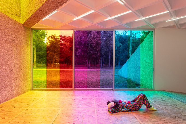 Installation view of colorful clown sculptures and rainbow colored windows by Ugo Rondinone