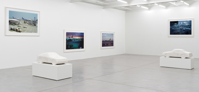 installation view of photographs of airports and car sculptures by Peter Fischli and David Weiss