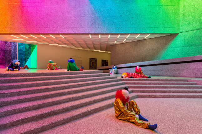 Installation view of colorful clown sculptures and rainbow colored windows by Ugo Rondinone