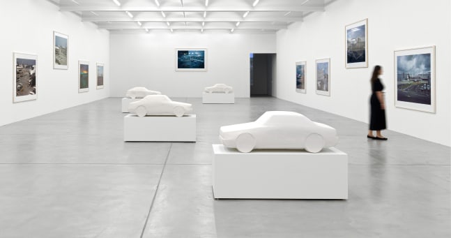 installation view of photographs of airports and car sculptures by Peter Fischli and David Weiss