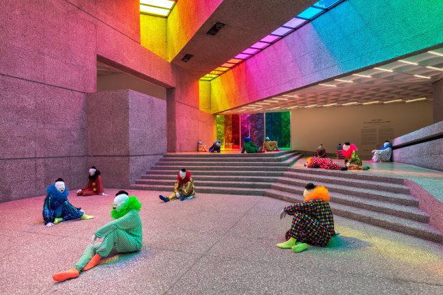 Installation view of colorful clown sculptures and rainbow colored windows by Ugo Rondinone