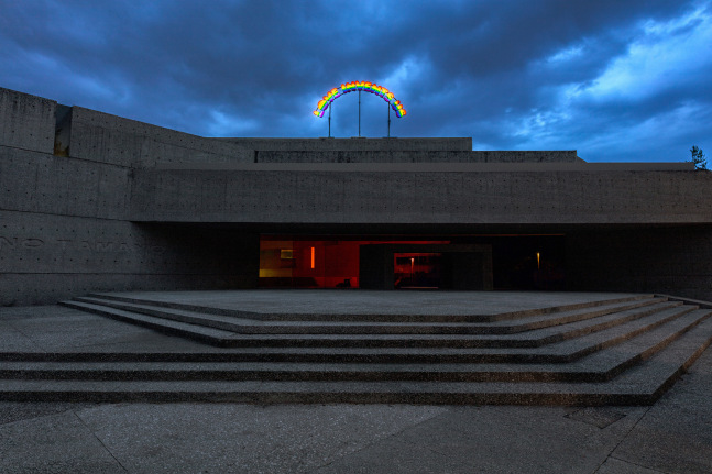 Installation view of colorful clown sculptures and rainbow colored windows by Ugo Rondinone